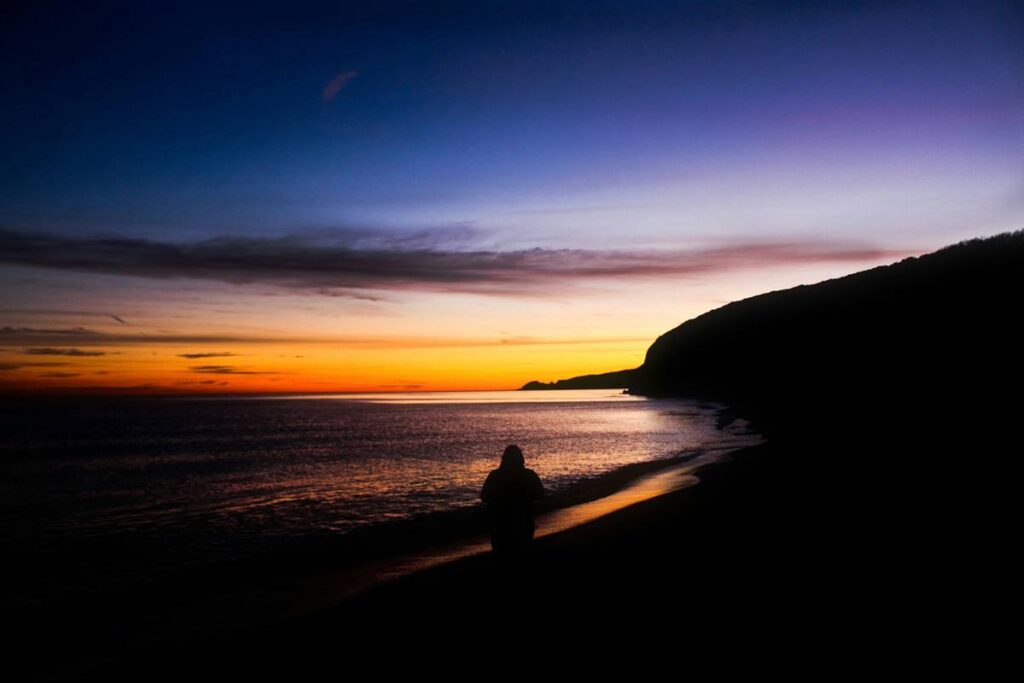 Silhouette of Person Standing on Beach at Surise